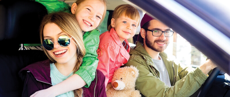 Mom and dad and 2 children in vehicle with teddy bear