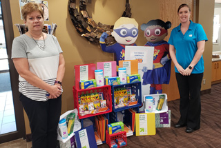 Mora First Citizens employees dressed in white short sleeve tshirts behind a Power Saver table