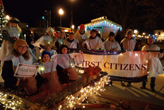 house built out of cereal boxes and cans beside a gingerbread man build out of cans
