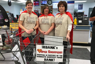 3 ladies dressed in cape behind a grocery shopping cart